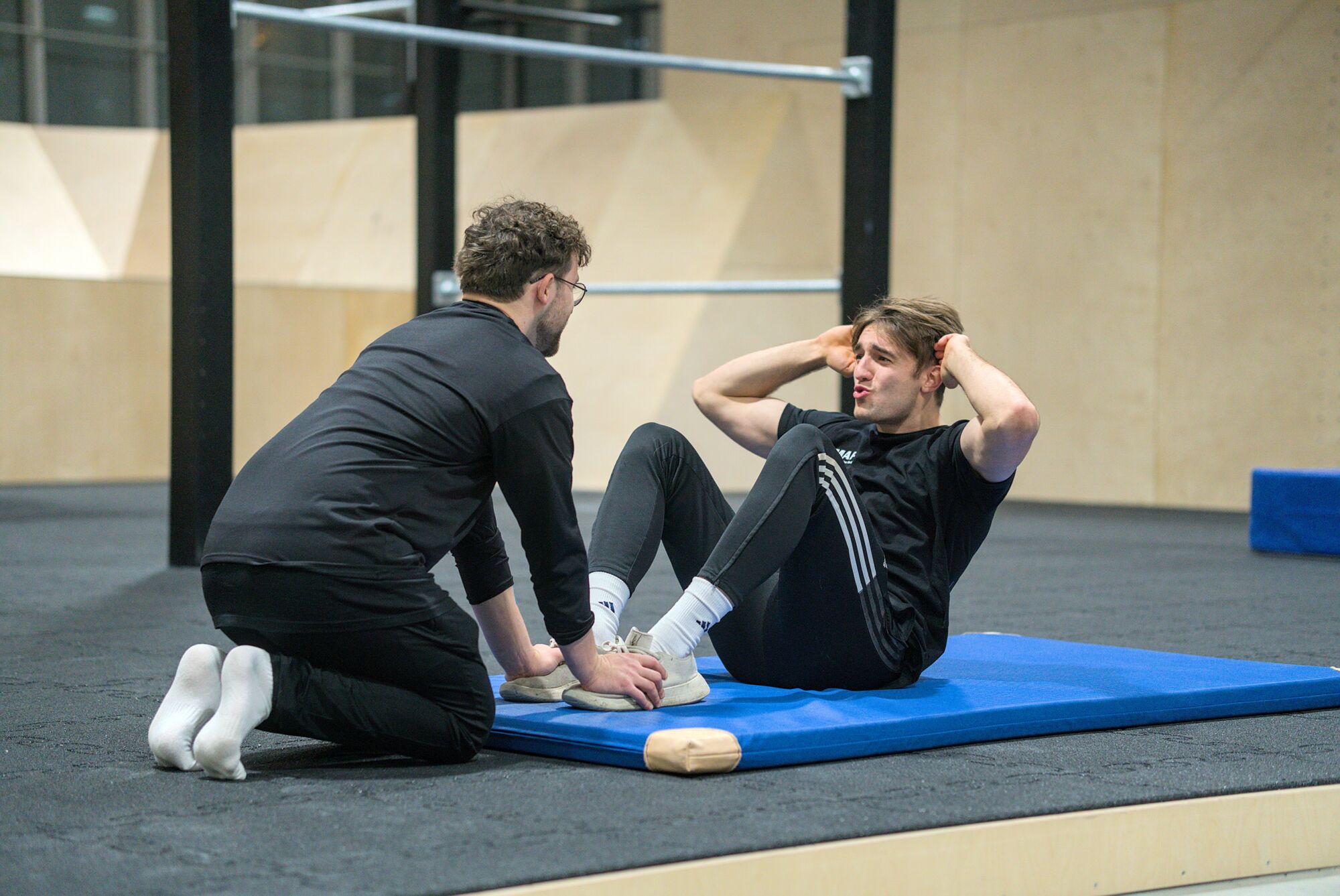 Personal Trainer gibt Hilfestellung bei Situps